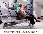 Women talking each other at hospital waiting area. African american man talking to general practitioner. People awaiting in sanatorium admissions section. Elderly lady explaining condition to girl.