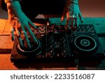 Performer artist mixing sounds at dj turntables, using audio equipment to play music and do musical remix performance. Having fun with volume instrument, nightclub party. Close up.