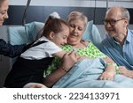 Small photo of Relatives bidding farewell to elderly woman suffering respiratory tract disease bedridden in medical clinic. Child hugging grandmother, saying goodbye before finishing visit to nursing home.
