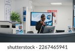 Small photo of African american receptionist working at hospital reception counter, answering landline phone call to make appointments for patients. Female facility employee using registration forms at front desk.
