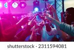 Small photo of Group of friends clinking glasses at dance party, serving alcohol drinks and saying cheers in discotheque. Cheerful people dancing and having fun at club, entertainment. Handheld shot.