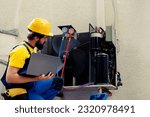 Small photo of Licensed technician commissioned for outside hvac system annual maintenance, looking for refrigerant leaks. Certified expert doing air conditioner inspection, imputing data on laptop