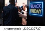 Small photo of Aggressive people arguing with security at clothing shop front door, waiting in line for black friday promotions. Bargan hunters rushing to enter retail store in search of deals and special offers.