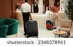 Small photo of Cheerful smiling concierge personnel helping tourists with accommodation booking. Helpful front desk receptionists answering questions about hotel room amenities during check in process