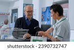 Small photo of Healthcare expert at chemist shop counter scanning pharmaceutical items from elderly client shopping basket. Octogenarian man buying fever lessening medicaments in pharmacy