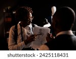 Small photo of Experienced fashion designer showing couturier sketch drawing of wedding dress she wants him to customize. African american dressmakers working on stylish bespoke sartorial attire