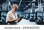 Small photo of Senescent professional navigating network of server rigs in industrial nexus. Employee with tablet doing analysis and optimizations in high tech data center, preventing system perils