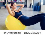 Woman doing abdominal crunches pilates exercise on exercise fitness ball at gym. Exercises for the abs. Swiss ball. Effort, dedication and motivation concept.