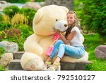happy girl hugs her beloved big teddy bear in the park on the stairs