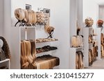 Showcase of natural looking wigs in different colors fixed on the metal wig holders in beauty salon. Row of mannequin heads with variation shades hair on shelf in wig shop