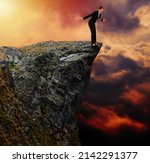 Small photo of Businesswoman on the edge of a high cliff looking down into the abyss, balancing herself in precarious equilibrium