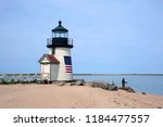 Fishing off the sandy beach by Brant Point lighthouse on Nantucket Island in Masssachusetts. The beacon is wrapped in an American flag to welcome visitors to the island.