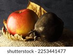 Small photo of RED RIPE APPLE AND OLD SPOILT POMEGRANATE ON A PIECE OF HESSIAN