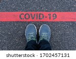 man in sneakers standing next to a red line with text COVID-19, restriction or safety warning concept