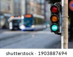blurred view of city traffic with traffic lights, in the foreground a traffic light with a green light