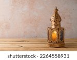 Small photo of Lightened lantern on wooden table over stone wall background. Ramadan kareem holiday celebration concept