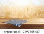 Empty wooden table with tablecloth over wheat field blurred background. Shavuot holiday mock up for design and product display