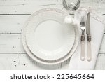 White table setting from above. Elegant empty plate, cutlery, napkin and glass on shabby chic or vintage planked wood table.