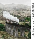 Small photo of Landscape with viaduct and train. Glenfinnan viaduct in scotland. Retro steam locomotive steam train railway in the mountains.