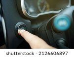 Driver pushing a vehicle engine start button, a modern car with keyless and go technology. Man pressing engine ignition button in a modern car on the control panel.