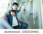 Happy cheerful Asian father and son traveling in the city on the sky train, man taking his lovely son travel on the city sky train.