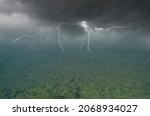 Dangerous lightning over green rainforest in rainy storm season in Asia