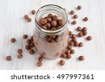 Chocolate milk with chocolate cereal balls in a glass jar on a white wooden table