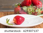 Strawberries in a transparent box on wooden background.