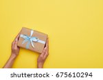 Flat lay of fantastic wrapped present decorated with bow on yellow background