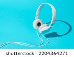 White levitating headphones. Isometric view of headphones on turquoise blue background. Dj headphones with cable.