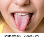 Nice girl showing her tongue. Child puts out tongue - close up.