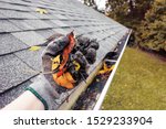 Small photo of Cleaning leaves and debris out of rain gutters in autumn