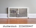 Dirty register wall vent with dust clogging the duct opening in a home 