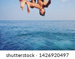 Young man jumping off cliff into blue water ocean at sunset. Active outdoor, holiday adventure, tourism action, healthy summer joy, Fun activity lifestyle. Crazy adult guy in swimwear fly from climb