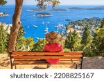 Small photo of Girl tourist resting on a bench with a top view of the City Harbour and marina of the town of Hvar, on the island of Hvar, the Adriatic coast of Croatia