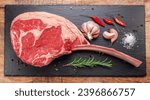 Small photo of Raw rib steak with bone or tomahawk steak with seasonings on slate serving plate. Flat lay.
