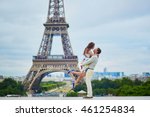 Happy romantic couple hugging near the Eiffel tower in Paris, girl is jumping, Tourists enjoying their vacation to France