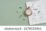 Small photo of vintage clock and grunge white yearly calendar, green thumbtack on grunge green background with copy space, business meeting schedule, travel planning or project milestone and reminder concept