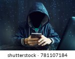 An anonymous hacker without a face uses a mobile phone to hack the system. Stealing personal data and money from Bank accounts. The concept of cyber crime and hacking electronic devices
