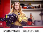 Photo of woman firefighter with helmet in her hands standing near fire truck
