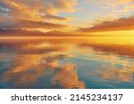 Bright sunset over lake Geneva, Switzerland, golden clouds reflect in the water
