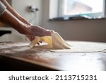 Low angle view of a woman making homemade strudel pastry dough on a flour dusted dining table.