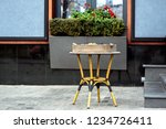 Small photo of Wicker table with a box of traditional Italian unary facade of a dark-colored restaurant with a flower pot under the window.