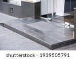 Small photo of marble gray porch step with a foot mat at the entrance to the central door made of tempered glass on floor iron hinges modern architecture with a stone apron of the building facade, nobody.