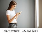 Young woman holding smartphone, typing message, chatting with friends in social networks.