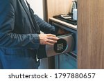 Adult man in blue jacket uses safe in the hotel room