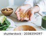 Woman doctor nutritionist hands in white shirt with omega 3, vitamin D capsules with green vegan food. The doctor prescribes a prescription for medicines and vitamins at clinic, healthy food