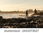 Small photo of silhouette of two fishermen pulling their trammel net on the beach shore, during sunset