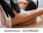 Small photo of A master cosmetologist in black gloves applies talcum powder to the armpit area for further depilation. epilation procedures. hair removal. Details of epilation process