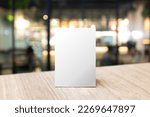 Mock up Label the blank menu frame in Bar restaurant. Stand for booklet with white sheet paper acrylic tent card on table wiht blurred background can inserting the text or picture.